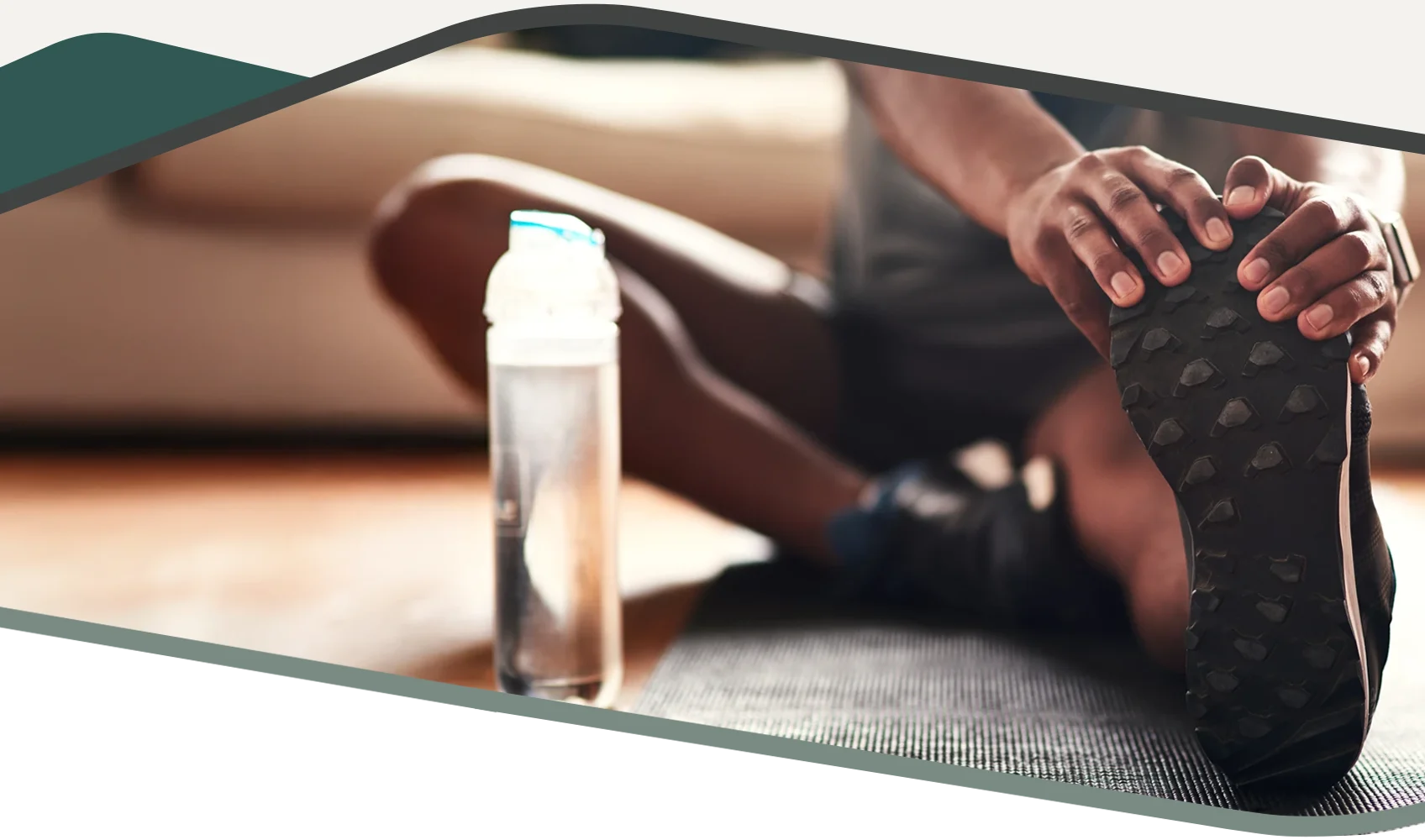 A person stretching their leg on a yoga mat. They have a bottle of water next to them.